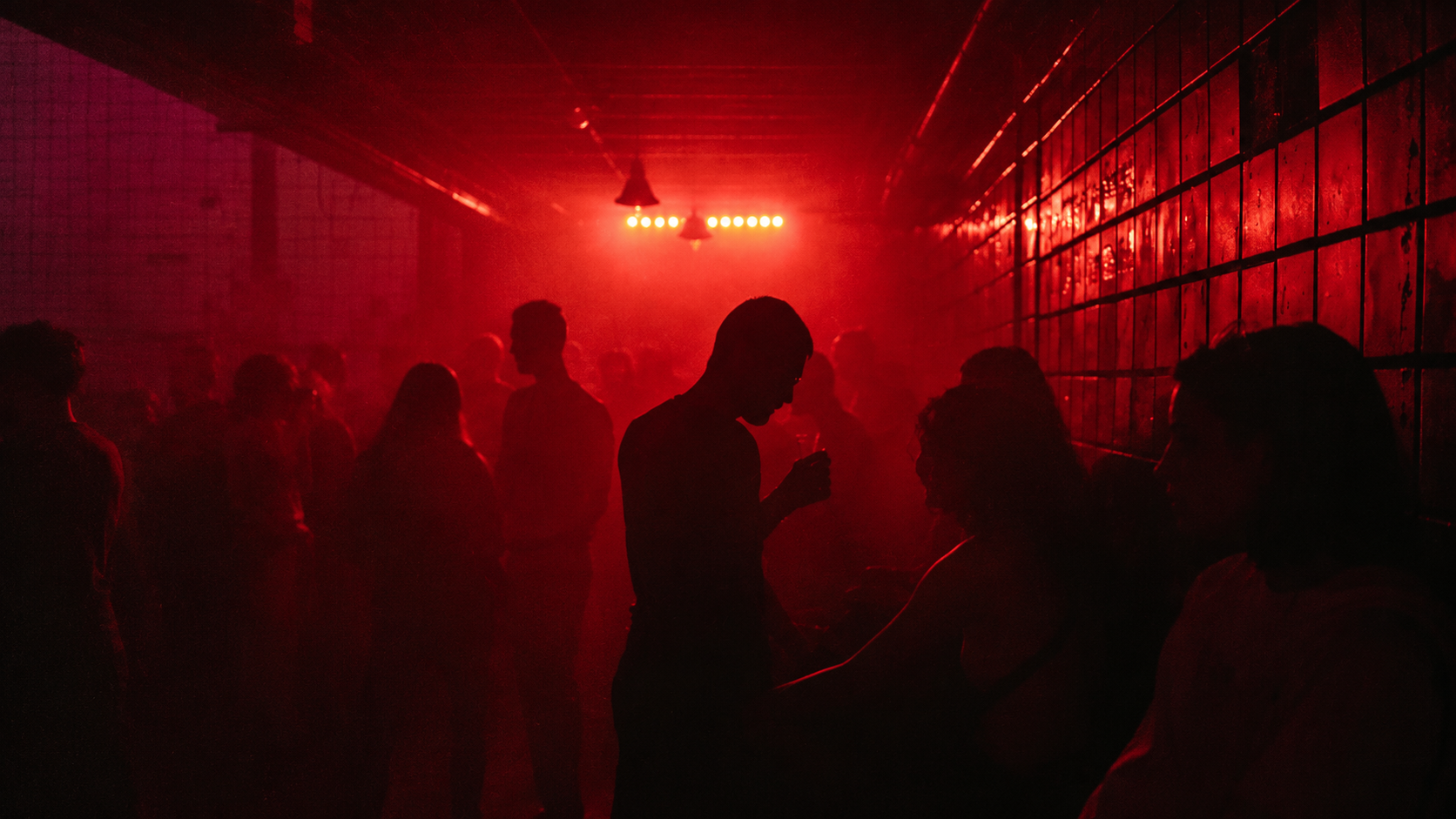 Anonymous silhouettes in a red-lit underground music room; original conceptual cover art